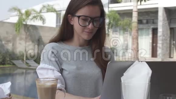 美丽的年轻女子在豪华别墅游泳池附近的笔记本电脑上工作女性在电脑上工作热巧克力可可视频的预览图