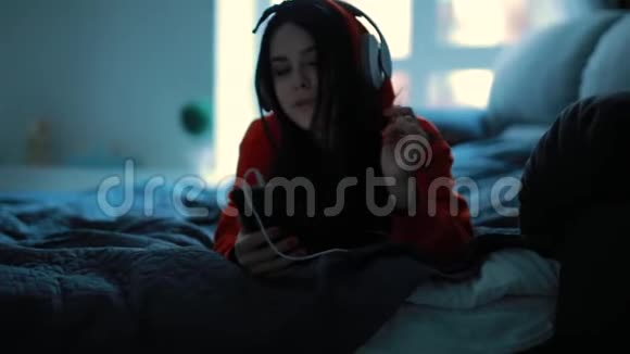 躺在床上听耳机音乐的女孩视频的预览图