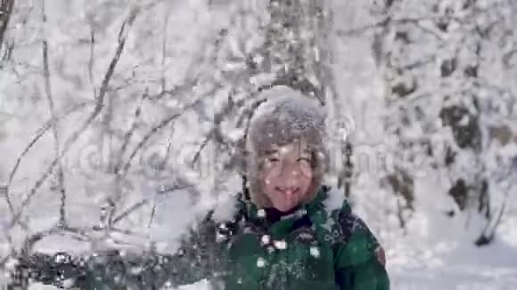 快乐迷人的孩子摇着一根白雪覆盖的树枝慢悠悠的动作视频的预览图