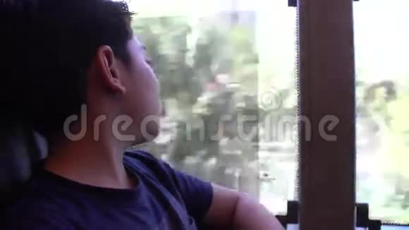 疲惫的小男孩坐公共汽车透过窗户看着视频的预览图