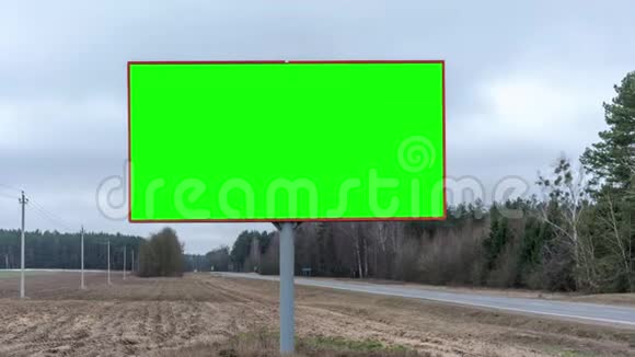 靠近灰色沥青路的带绿色屏幕的广告牌视频的预览图
