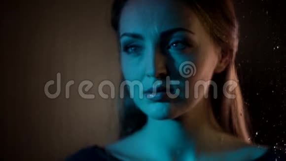 迷人的梦幻的年轻的白种人女人看着玻璃窗用指尖在夜蓝色的霓虹灯中画出一颗心视频的预览图
