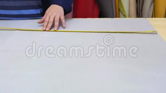 在一家家具厂里一位年长的妇女正在用一个衬衫为沙发测量和标记一种灰色材料视频的预览图