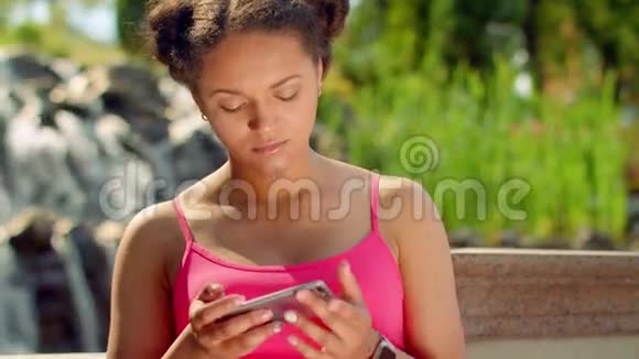 在公园用智能手机的拉丁女孩体贴的女孩在电话里上网视频的预览图