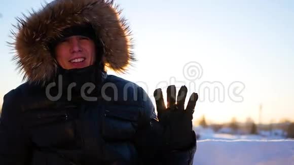 那个人挥动着他的手在冬天在日落的时候快乐地笑着冬天的雪景户外视频的预览图