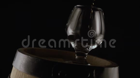 干邑的杯子在木桶上黑色背景慢节奏视频的预览图