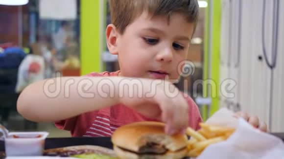 午餐在学校自助餐厅享用汉堡和薯条作为儿子的零食小男孩胃口大开视频的预览图