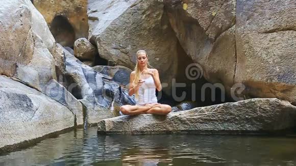 金发女郎坐在石头上的莲花里返回水瓶视频的预览图