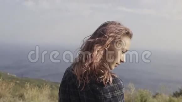蓝色海景的山顶上站着一头粉红色头发的女人视频的预览图