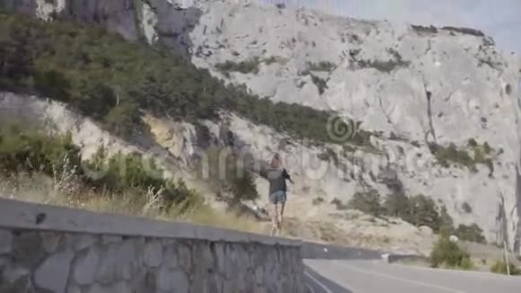 美丽的瘦小女孩沿着岩石背景上的护栏奔跑视频的预览图