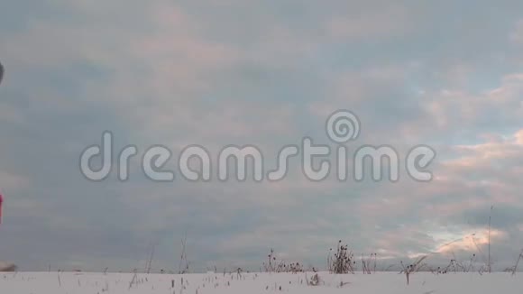 穿着银色夹克和红色马裤的年轻女子在天空中的雪地上行走视频的预览图