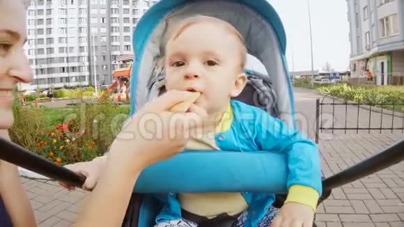 小男孩坐在婴儿车里吃饼干的慢镜头视频的预览图