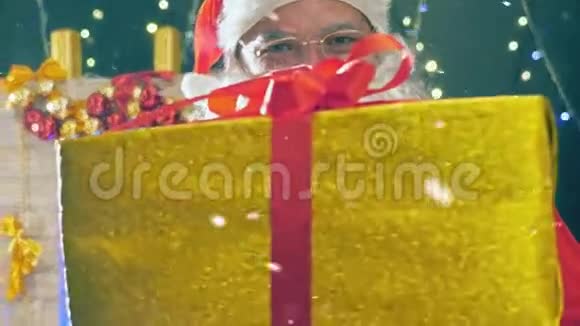 圣诞老人手里拿着带红丝带的金色礼盒视频的预览图