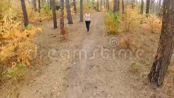 秋天森林里美丽的金发美女慢跑的慢镜头视频的预览图