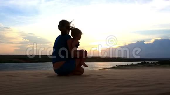 剪影母囊在黄昏的湖边载着小女孩视频的预览图