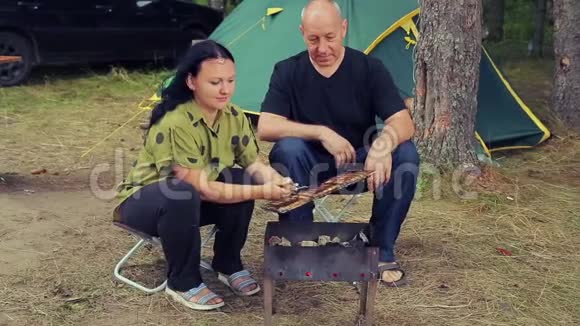 一男一女在帐篷烤鱼烤架上视频的预览图