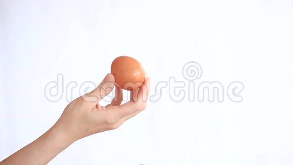 女人的手在白色的背景上拿着一个鸡蛋视频的预览图