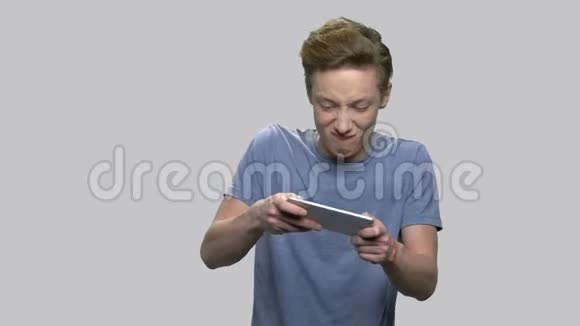 情绪化的男孩在智能手机上玩游戏视频的预览图