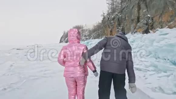 在冰封的湖面上年轻夫妇在冬天散步时玩得很开心恋人们在冰上行走彼此拥抱视频的预览图