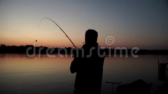 剪影渔夫在日落的背景下向河里扔鱼竿视频的预览图