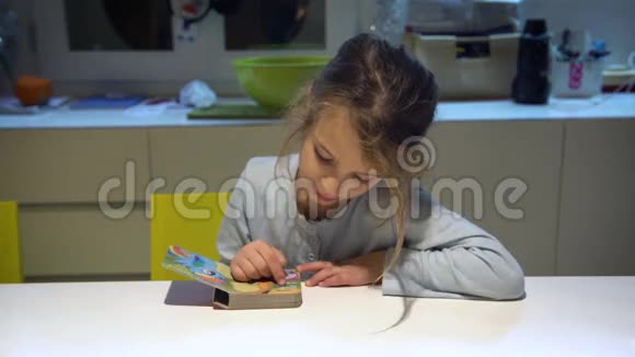 一个六岁的棕色头发的女孩穿着睡衣看着一本小书视频的预览图