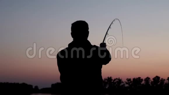 剪影渔夫在日落的背景下向河里扔鱼竿视频的预览图
