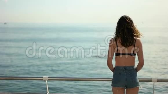 穿短裤的布鲁尼特女孩看着大海视频的预览图