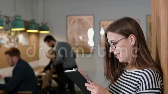 在现代创业团队中漂亮的黑发商务女性在工作场所使用平板电脑视频的预览图