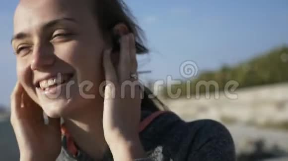 年轻风趣开朗的女人听着耳机里的音乐微笑欢笑和舞蹈视频的预览图