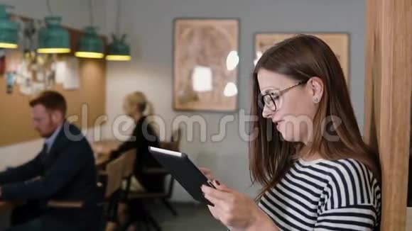 在现代创业团队中漂亮的黑发商务女性在工作场所使用平板电脑视频的预览图