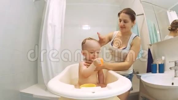 年轻的母亲在浴室里洗婴儿头视频的预览图