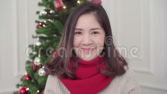 圣诞快乐的年轻亚洲女人微笑着在家里的客厅里拍照视频的预览图