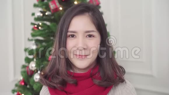 圣诞快乐的年轻亚洲女人微笑着在家里的客厅里拍照视频的预览图