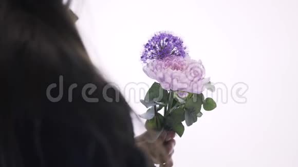 一个女花店把一束紫色白色和粉红色的花收起来视频的预览图