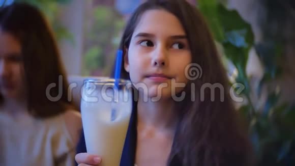 女孩喝奶昔坐在咖啡馆慢动作视频视频的预览图