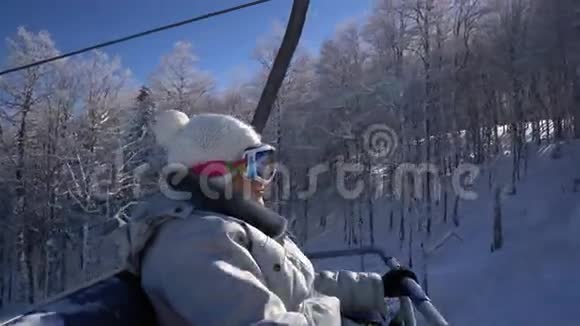 快乐的滑雪者女人站在电梯上爬到山顶视频的预览图