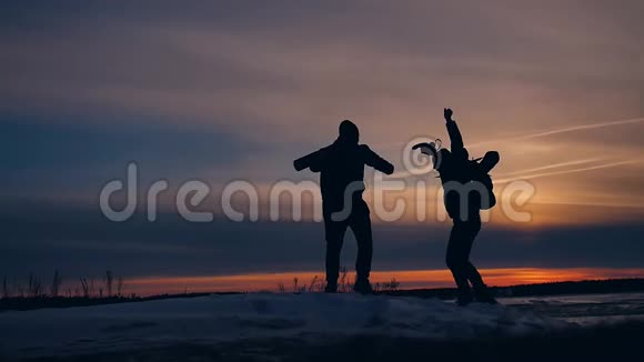 两名游客在夕阳下奔跑跳跃剪影有趣的积极自然景观冬季雪两名男性摄影师视频的预览图