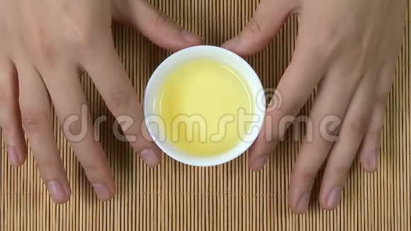 女双手捧着白杯的中国茶竹背景俯视图一个女人拿着一杯茶绿色日本视频的预览图