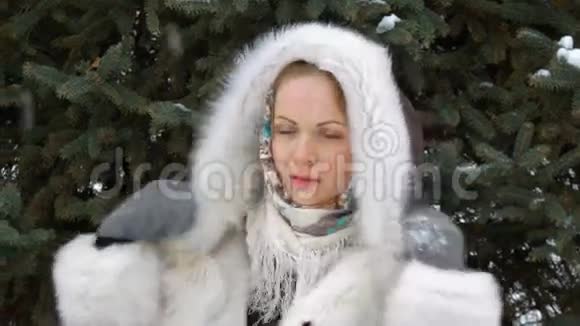 一个美丽的时尚模特微笑和看镜头冬天飘雪特写视频的预览图