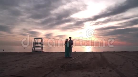 一对怀孕的夫妇在日落时分聊天爱情观念海边的浪漫情侣视频的预览图