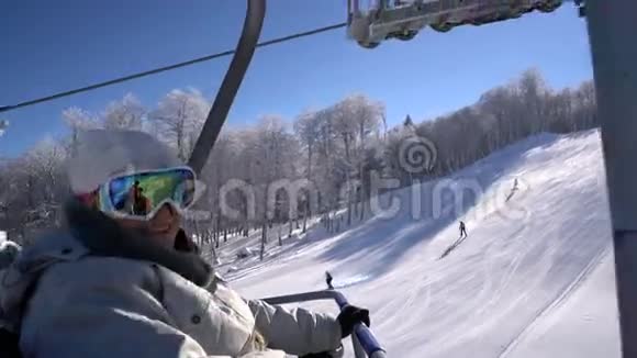 快乐的滑雪者女人站在电梯上爬到山顶视频的预览图
