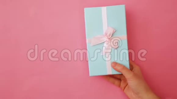 简单设计女性手拿蓝色礼品盒隔离粉彩贴色彩缤纷时尚背景视频的预览图