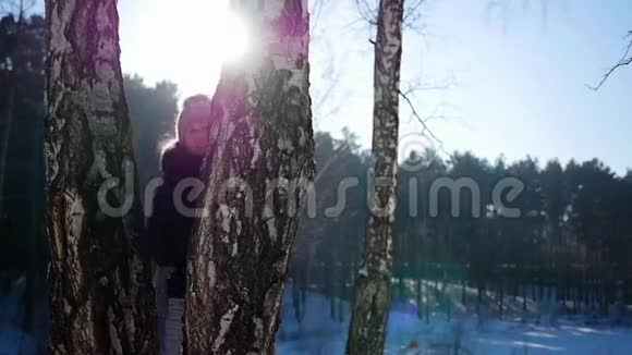 一个女孩从树后面扔雪球下雪的冬天的风景晴天视频的预览图