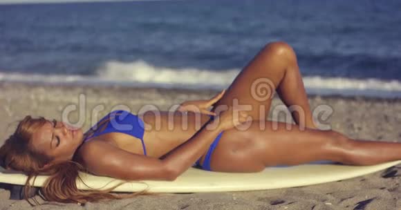 在日光浴的时候女人在冲浪板上休息视频的预览图