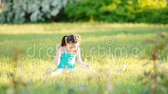 可爱的小女孩坐在草地上夏天在公园里玩视频的预览图