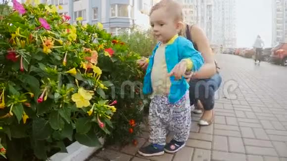 可爱的小男孩妈妈看着街道上生长的花朵视频的预览图