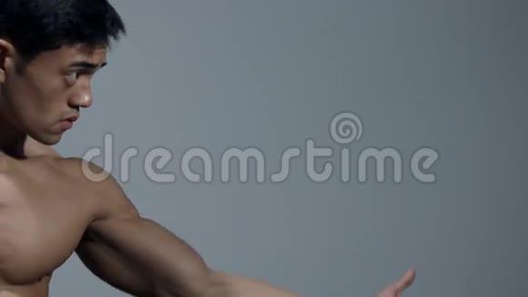 男性健身模特将手臂伸出弯曲他的双头肌视频的预览图