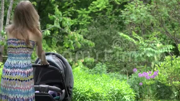 穿着衣服的女人试图让婴儿睡在花园里的婴儿车里4K视频的预览图