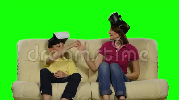 虚拟现实面具年轻的母亲和她的儿子愉快地玩着头戴式的展示绿色屏幕视频的预览图