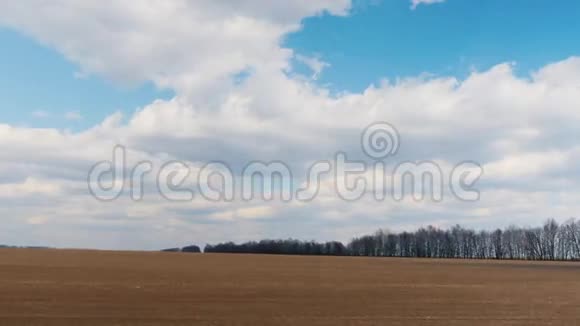 早春时节沿着犁过的田地快速行驶可见的农田和蓝天白云POV窗口视频的预览图